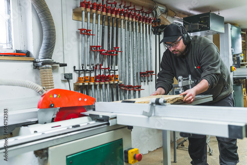 A carpenter cutting timber on a sliding saw table at his workshop. High quality photo
