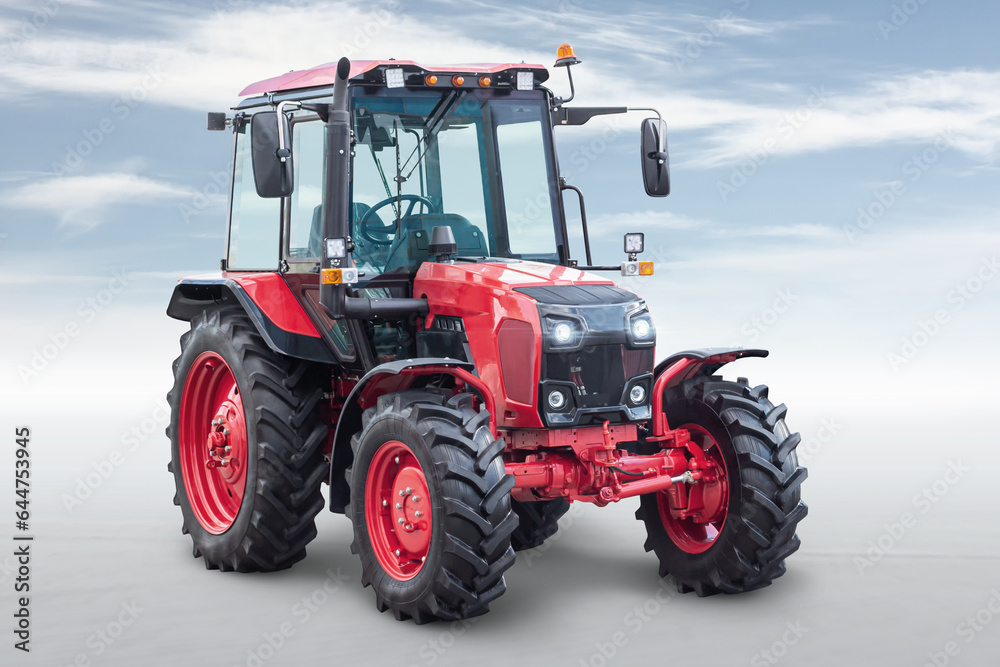 Red modern wheeled tractor isolated on bright background with sky