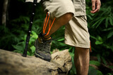 Male hiker with backpack walking cross tree trunk, exploring nature in forest. Traveling and adventure concept