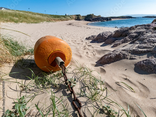 Orange buoy lying on the beach at low tide photo