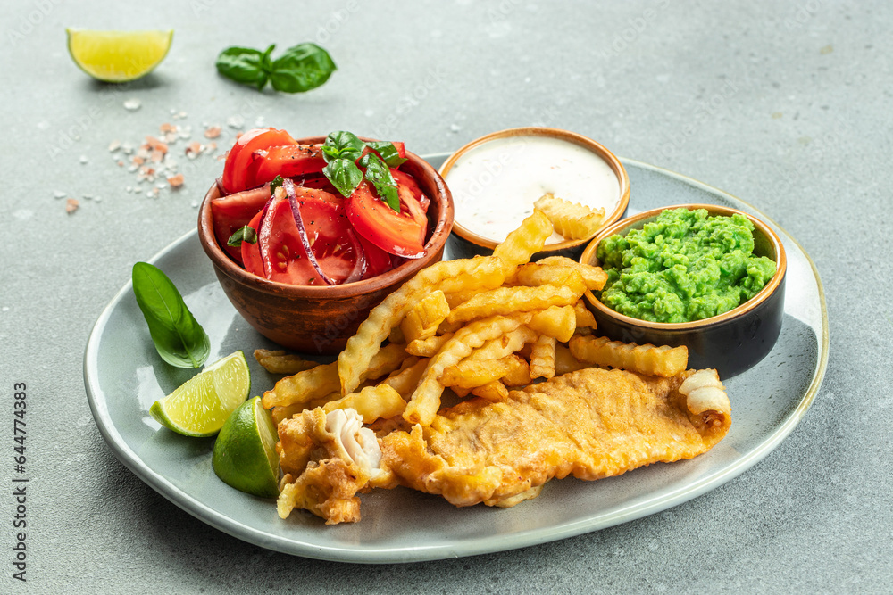 Fish and chips with green peas, vegetable salad, tartar sauce, British cuisine concept Fish and chips with green peas, vegetable salad, tartar sauce, British cuisine concept