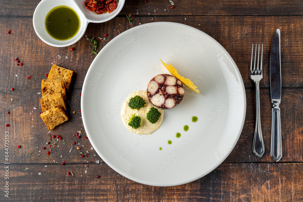 Octopus terrine or octopus carpaccio with sauces on a white porcelain plate Octopus terrine or octopus carpaccio with sauces on a white porcelain plate