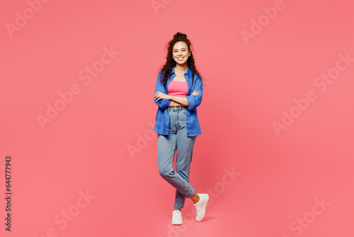 Full body smiling happy cheerful young woman of African American ethnicity she wearing blue shirt casual clothes hold hands crossed folded look camera isolated on plain pastel pink background studio.