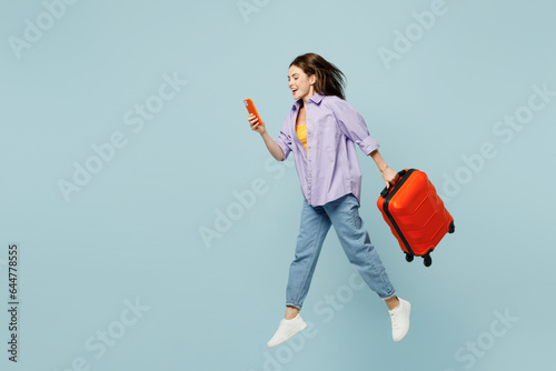 Fototapete Traveler woman wear casual clothes jump high run use mobile cell phone hold bag