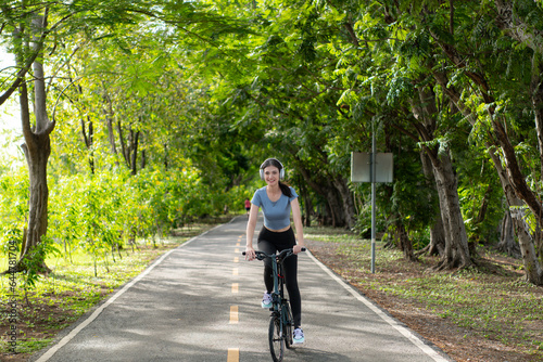 Wallpaper Mural Young woman listening to music with headphones while biking in the park Torontodigital.ca