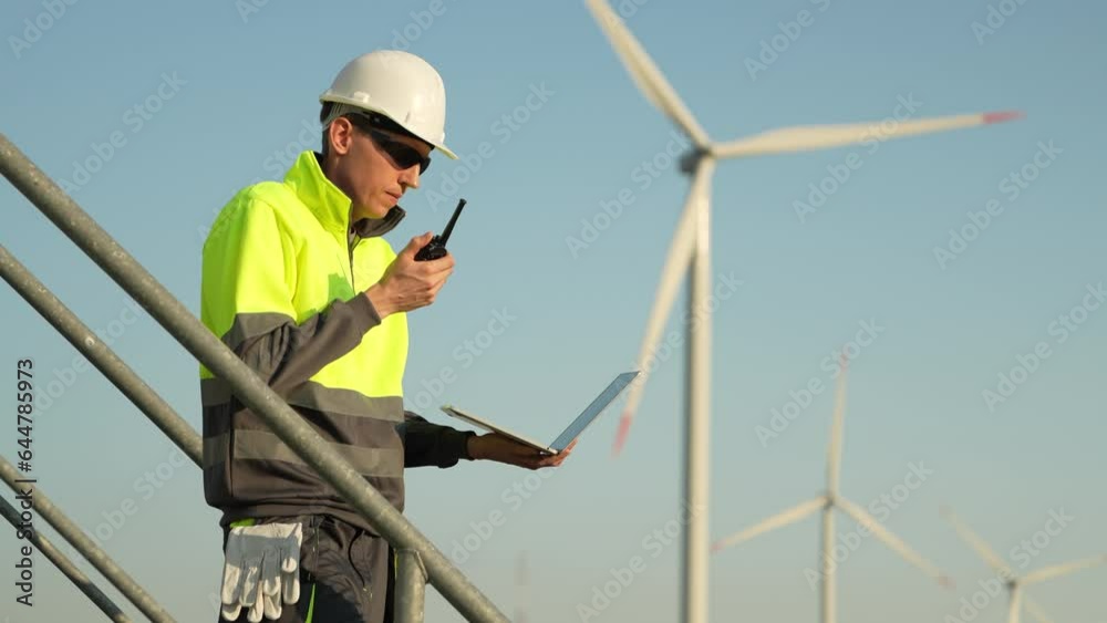 Engineer with a walkie-talkie on the background of wind turbines Engineer with a walkie-talkie on the background of wind turbines