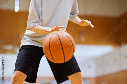 体育館でバスケットボールのドリブルを練習をするスポーツウェアを着た日本人女性 © west_photo