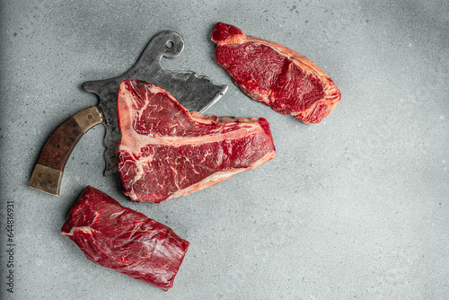 Meat Steaks T-bone between knife, on stone background. Raw beef meat. place for text, top view