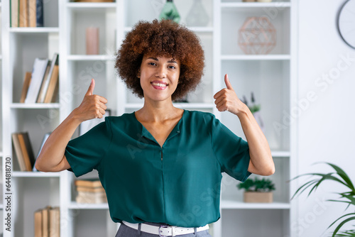 confident afroamerican woman showing two thumb up in approval, recommending, standing over home office background