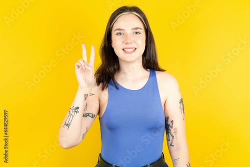 Beautiful woman wearing blue tank top showing and pointing up with fingers number two while smiling confident and happy.