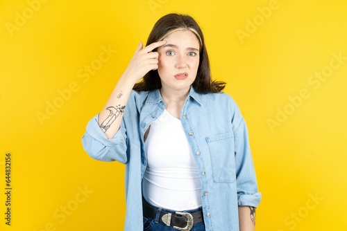 Beautiful woman wearing casual clothes pointing unhappy at pimple on forehead, blackhead  infection. Skincare concept.