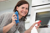 woman is cleaning an oven with spray