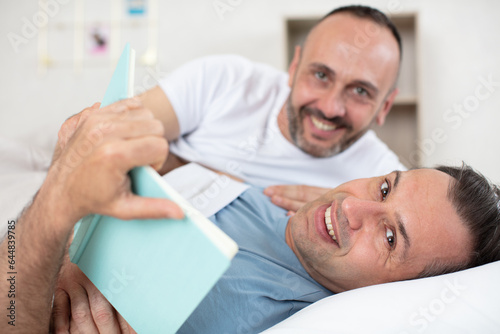 happy gay couple reading book on bed