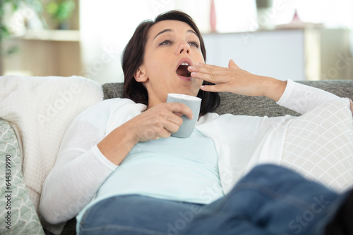 attractive woman holding smartphone and yawning