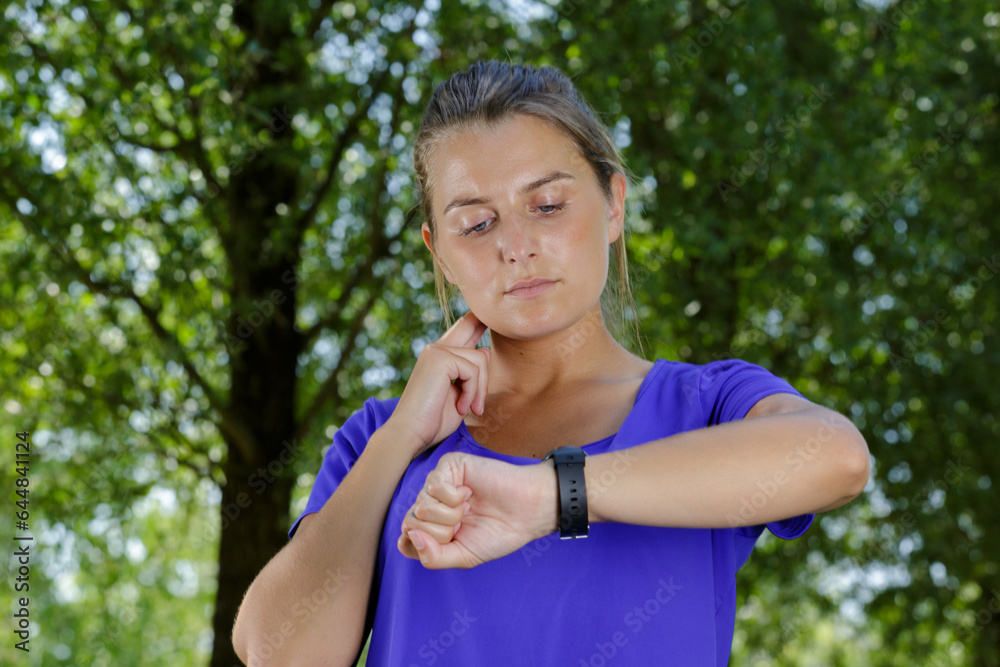 Fototapeta premium young woman checking her pulse outdoors after running
