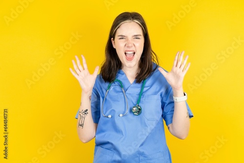 Crazy outraged Young caucasian doctor woman wearing blue medical uniform screams loudly and gestures angrily yells furiously. Negative human emotions feelings concept