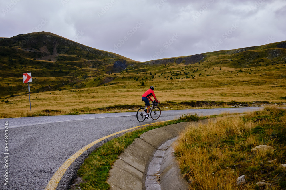 Male cyclist riding a gravel bike in the mountainous terrain on a foggy day.Man cyclist wearing cycling kit and helmet.Motivation image of an athlete.Cyclist enjoying traveling on his bike.Transalpina Male cyclist riding a gravel bike in the mountainous terrain on a foggy day.Man cyclist wearing cycling kit and helmet.Motivation image of an athlete.Cyclist enjoying traveling on his bike.Transalpina