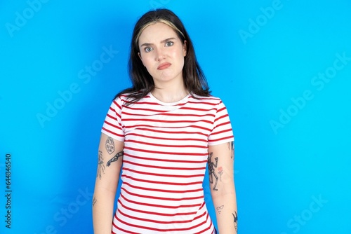 Displeased beautiful young woman wearing striped T-shirt frowns face feels unhappy has some problems. Negative emotions and feelings concept © Roquillo