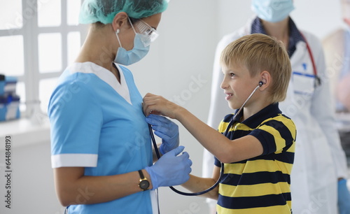 Boy in medical office listens to doctor s breath through stethoscope. Use of a stethoscope in medicine concept