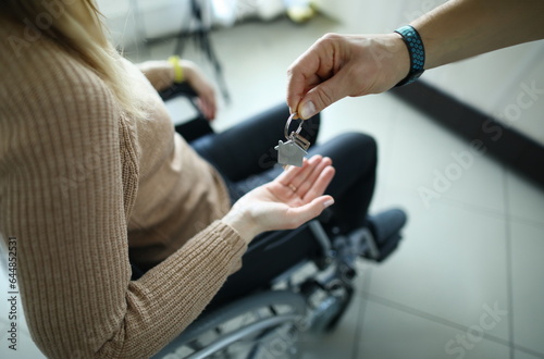 Fototapeta Woman is sitting in wheelchair and keys are handed over to her