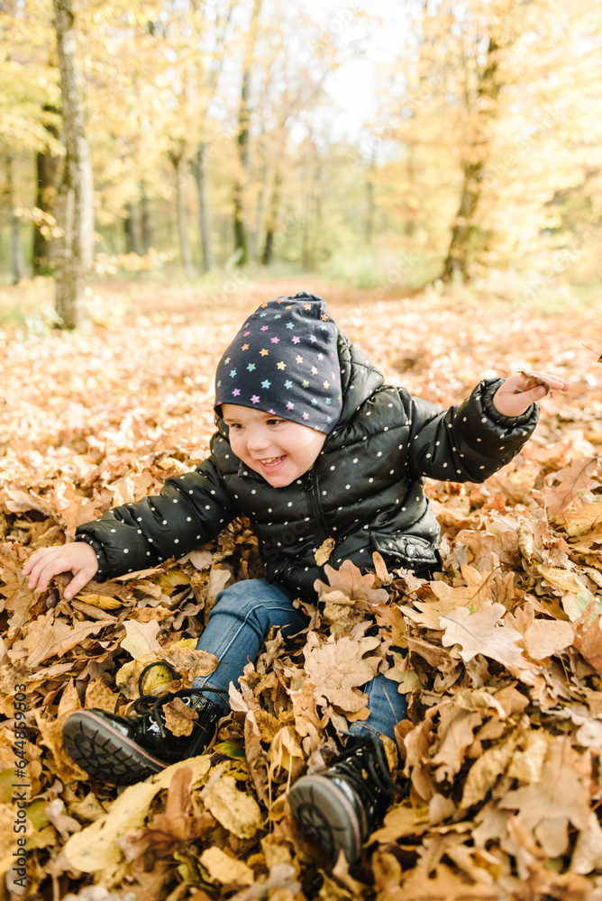 Child little girl throws up autumn leaves. Kid sitting on yellow leaves and playing in park. Family spending time together at sunset on vacation. Daughter walks in forest. Autumn holiday in nature. Child little girl throws up autumn leaves. Kid sitting on yellow leaves and playing in park. Family spending time together at sunset on vacation. Daughter walks in forest. Autumn holiday in nature.