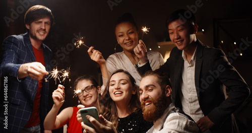 Positive multiethnic student friends celebrating together, having video chat with their friends or parents, cheering about christmas or graduation and smiling - communication, real people 