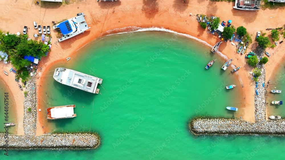 Breakwaters are constructed using massive concrete blocks, natural rock, or a combination of both. From a drone's viewpoint, these materials create a textured pattern of irregular shapes and sizes.
