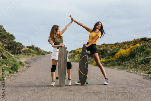 Cheerful diverse women giving high five on road