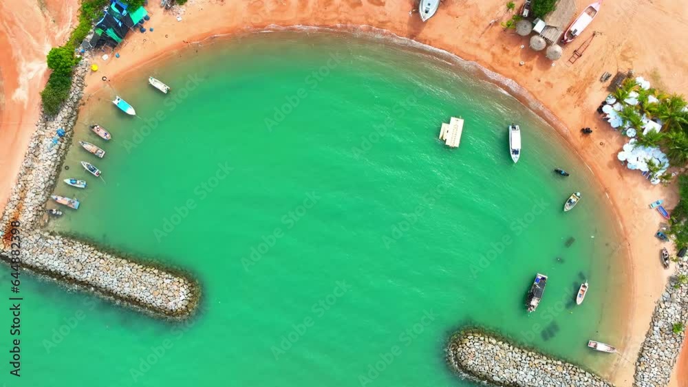 Breakwaters are constructed using massive concrete blocks, natural rock, or a combination of both. From a drone's viewpoint, these materials create a textured pattern of irregular shapes and sizes.
