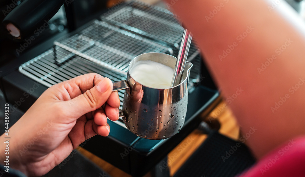 Professional barista warming milk for cappuccino. hand of Barista using the coffee machine for coffee latte