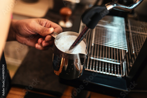 Close-up of Barista hand using high-pressure steam-operated milk frother to prepare a cappuccino coffee milk