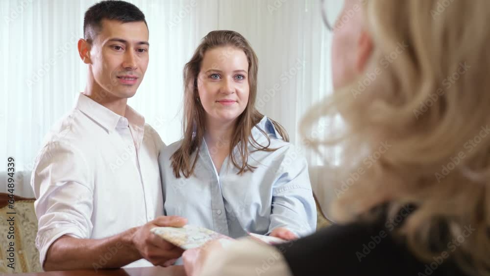 Young couple gives passports to receptionist to check personalities. Blonde receptionist checks passport to find reserved hotel room Young couple gives passports to receptionist to check personalities. Blonde receptionist checks passport to find reserved hotel room