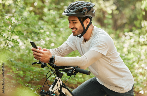 Fototapeta Naklejka Na Ścianę i Meble -  Man, forest and phone on bike, texting and smile for web chat notification on adventure in nature. Guy, cycling and smartphone for contact with bicycle, relax and social media app in woods on blog