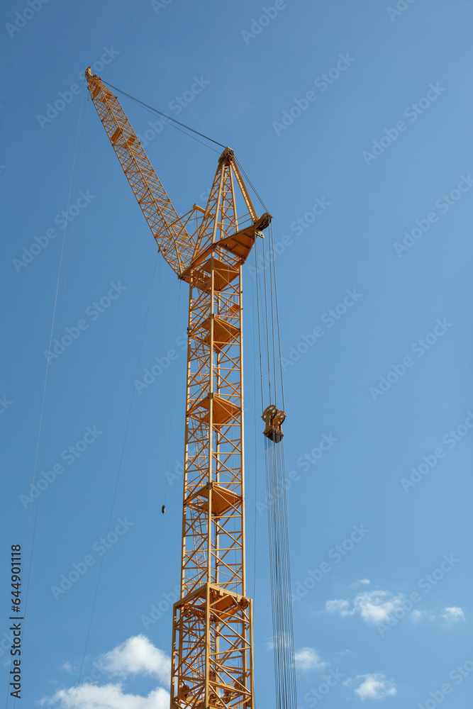Vertical Shot of Yellow Construction Crane Against Blue Sky Vertical Shot of Yellow Construction Crane Against Blue Sky