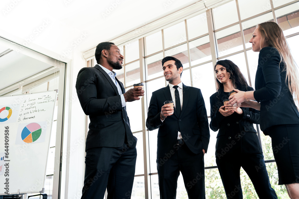 Diversity group of businesspeople strictly dressed in the suits standing meeting by office window. African and Caucasian white-collar workers having informal talking and discussion. Diversity group of businesspeople strictly dressed in the suits standing meeting by office window. African and Caucasian white-collar workers having informal talking and discussion.