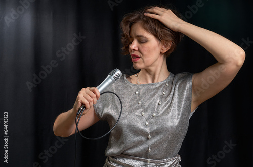 Portrait of a singing woman with a microphone in her hands on a black background