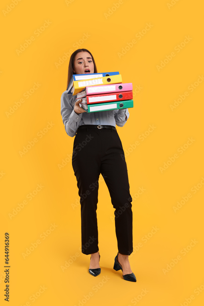 Stressful woman with folders on orange background Stressful woman with folders on orange background