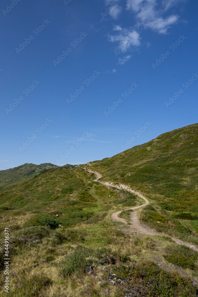 small path on top of a mountain with view towards alpine summits and sky