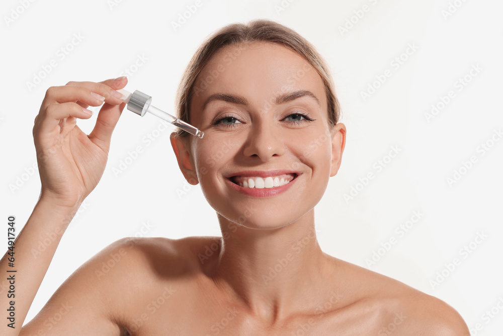 Beautiful woman applying cosmetic serum onto her face on white background Beautiful woman applying cosmetic serum onto her face on white background
