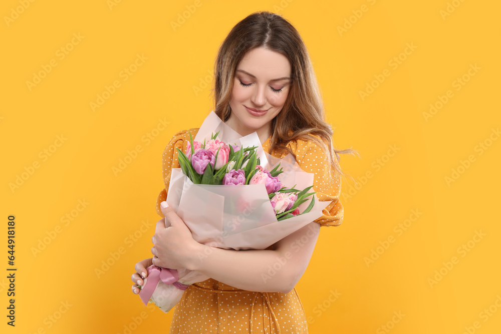 Happy young woman with bouquet of beautiful tulips on yellow background Happy young woman with bouquet of beautiful tulips on yellow background