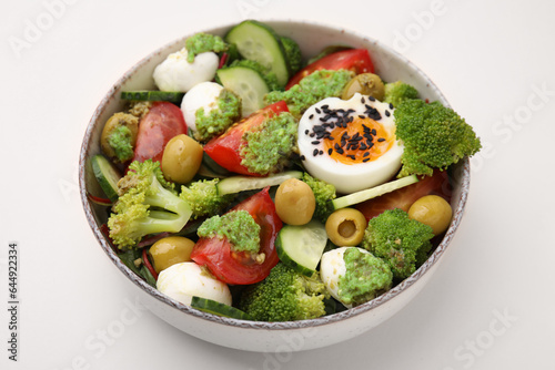 Delicious salad with pesto sauce in bowl on beige table, closeup