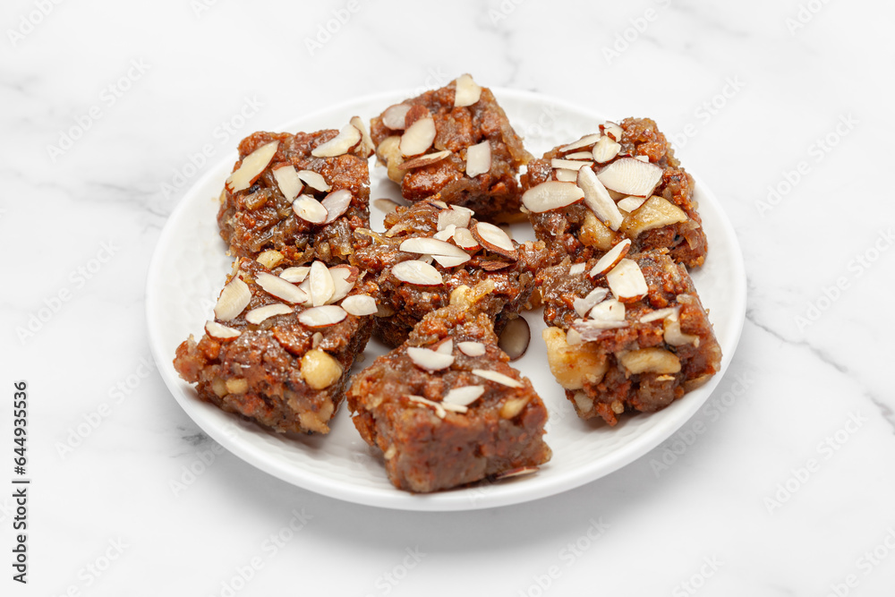 Close-up of Indian Dry fruits and nuts Barfi (sweet or mithai), on a white ceramic plate. Front view. Close-up of Indian Dry fruits and nuts Barfi (sweet or mithai), on a white ceramic plate. Front view.