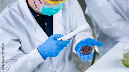 Scientist use magnifying glass to analyze soil, fertilizer or dirt sample. Biotechnology, agricultural, and geology laboratory. Exploration and developing quality of soil. Pollution and chemical test