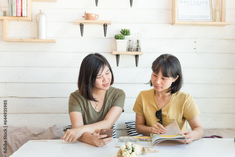 Happy asian woman friend sitting in cafe order some drink looking in menu Happy asian woman friend sitting in cafe order some drink looking in menu