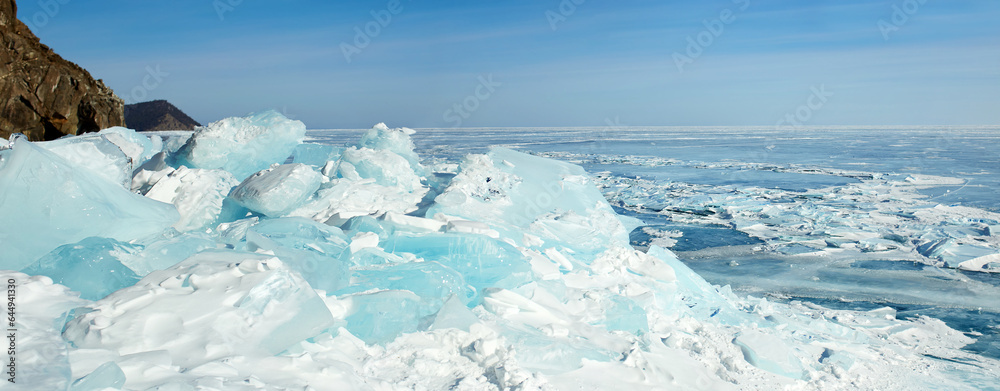 Huge blocks of transparent blue ice covered with snow, hummocks on the frozen Lake Baikal. Winter landscape, panorama