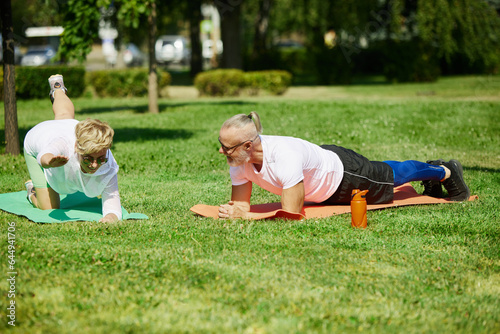 Early morning yoga. Mature couple, sportive man and woman training outdoors in park on warm summer day. Concept of active and sportive lifestyle, age, health care, exercising, ad