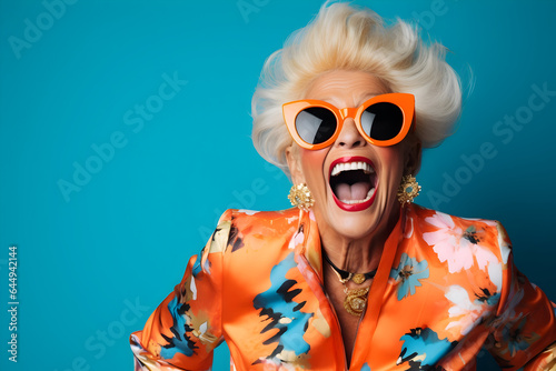 Vibrant Studio Fun A Happy Senior Woman Dressed in a Colorful Orange Outfit and Cool Sunglasses, Laughing and Having a Great Time in a Fashion Studio