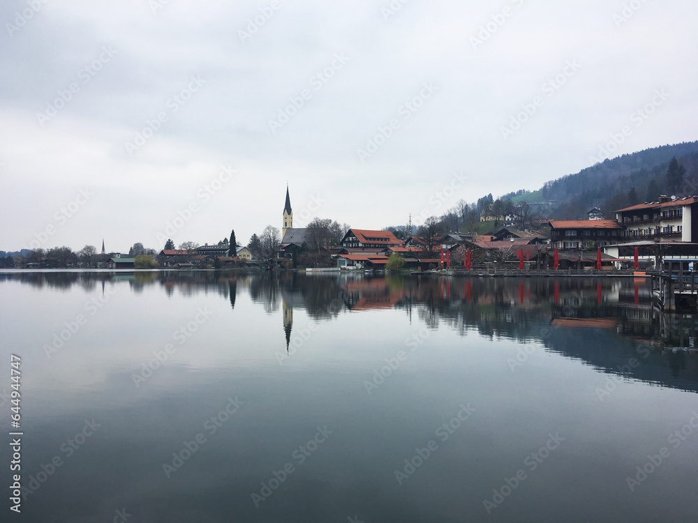 Scenic view of the town Schliersee reflected in eponymous lake against the cloudy sky, Bavaria, Germany, April 2019