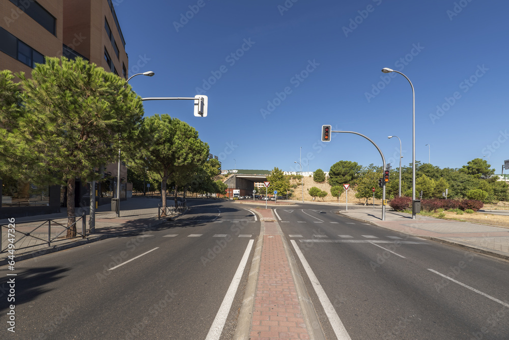 A two-way street with a large tree-lined roundabout