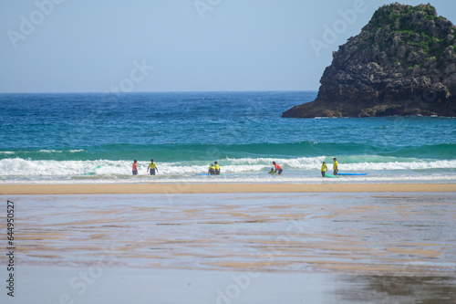 Young surfers train on Playa de Palombina Las Camaras in Celorio, Green coast of Asturias, North Spain with sandy beaches, cliffs, hidden caves, green fields and mountains photo